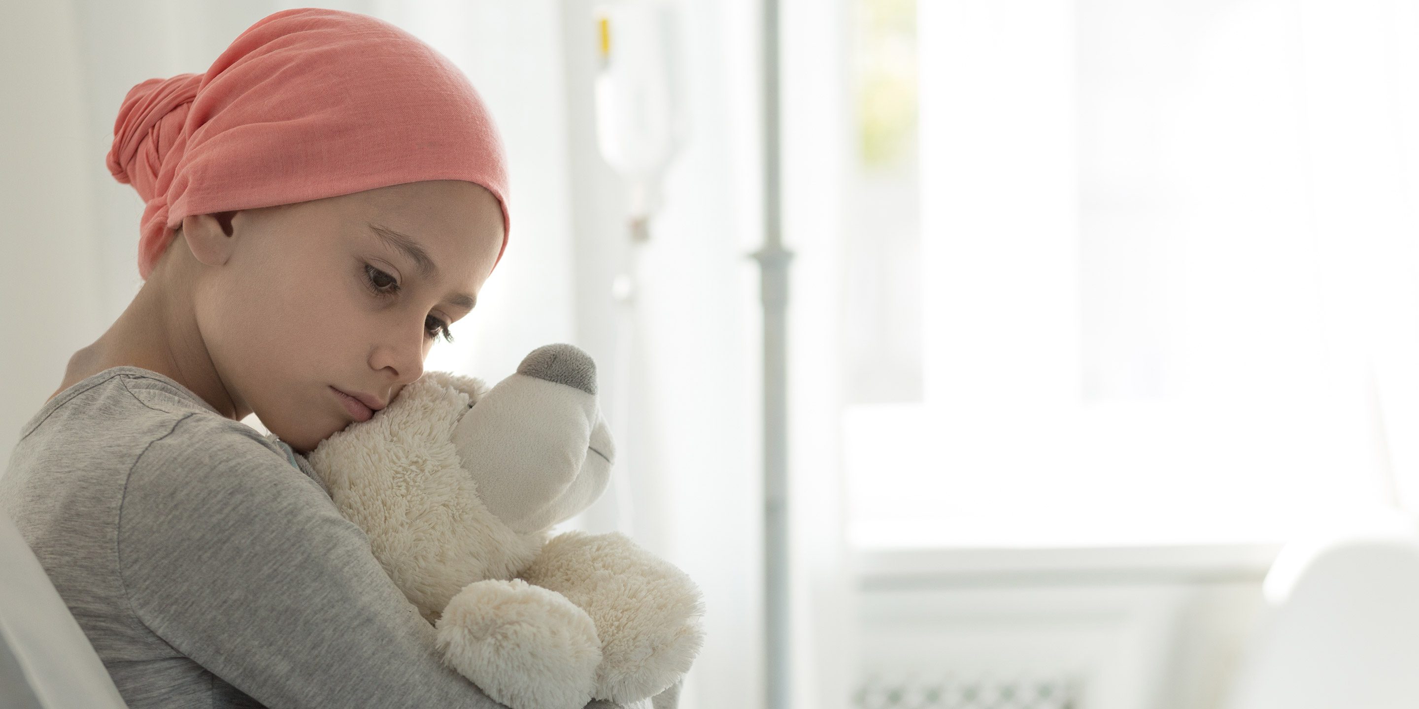 Mädchen mit Teddybär im Spitalbett